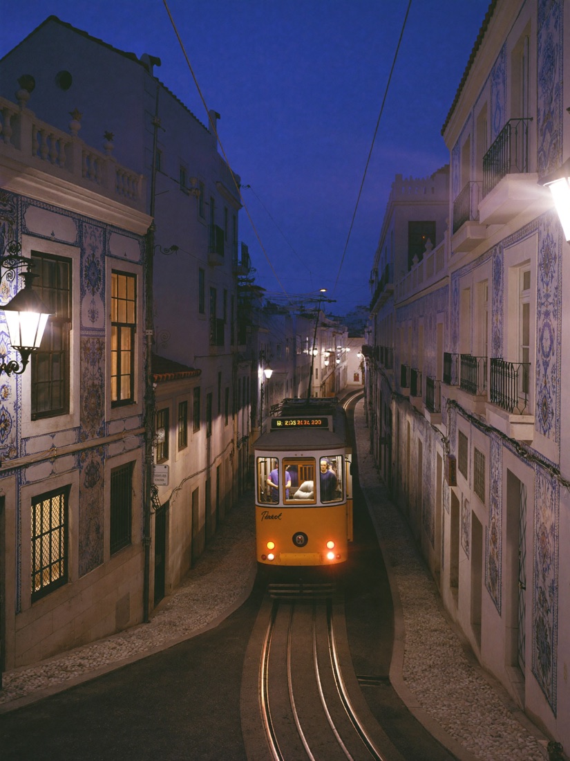 A yellow tram on a tiled Lisbon street