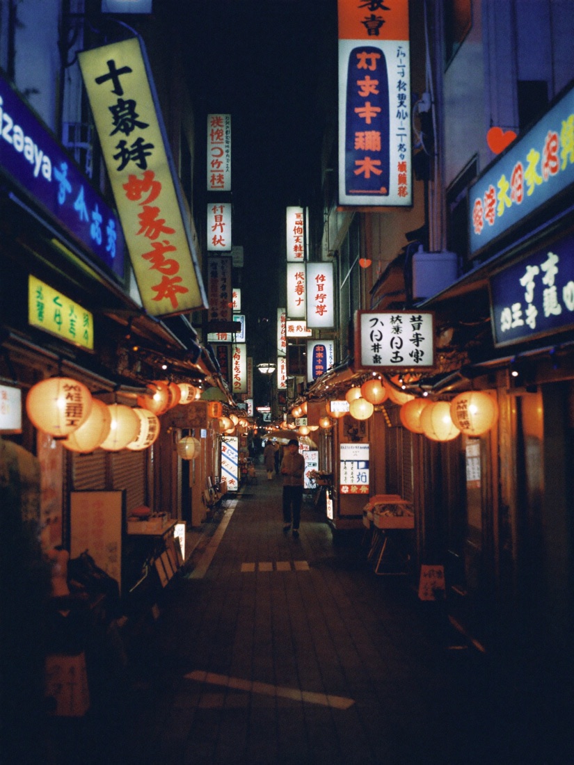 A narrow Tokyo lane lit by signs at night
